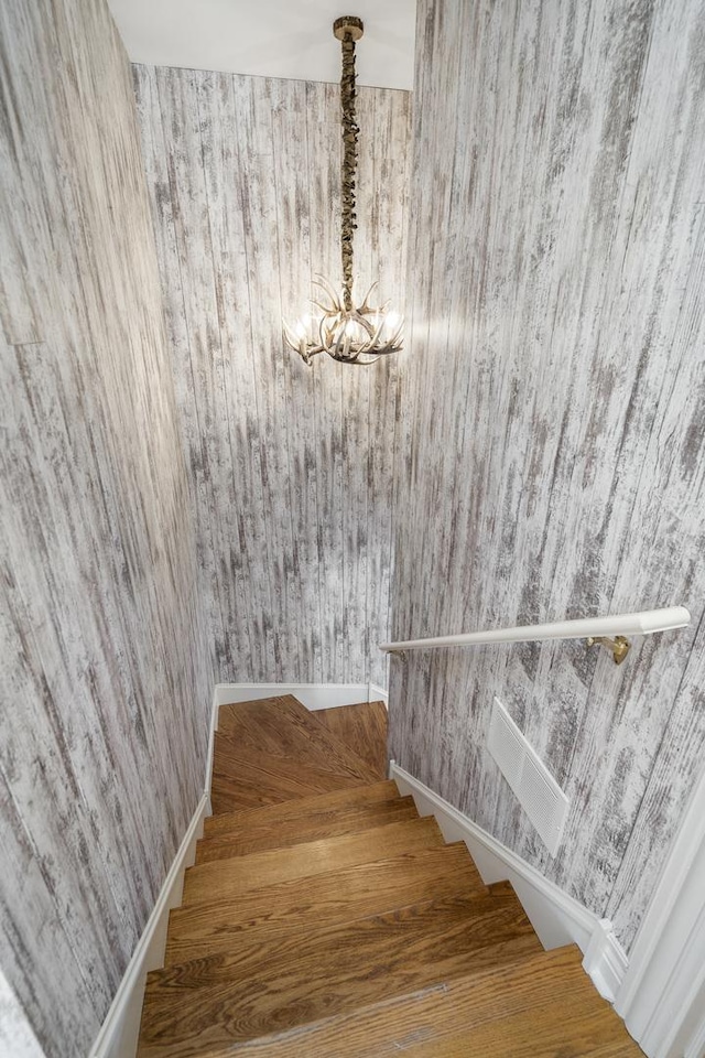 staircase with an inviting chandelier