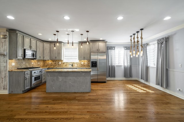 kitchen featuring light stone counters, pendant lighting, a center island, and stainless steel appliances