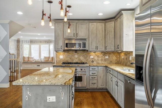 kitchen featuring sink, decorative light fixtures, a kitchen island, light stone counters, and stainless steel appliances