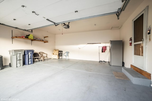 garage with a garage door opener and stainless steel refrigerator