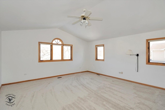 carpeted spare room featuring ceiling fan, vaulted ceiling, and a wealth of natural light