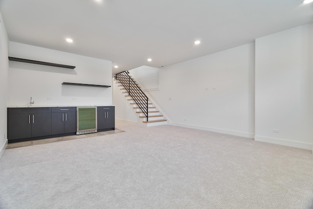 unfurnished living room with wet bar, light carpet, and beverage cooler