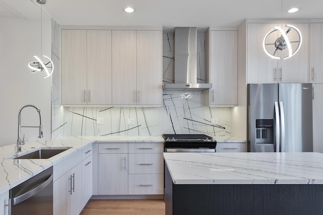 kitchen with light stone countertops, sink, stainless steel appliances, wall chimney range hood, and decorative light fixtures