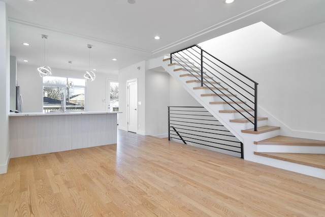 unfurnished living room featuring a notable chandelier and light hardwood / wood-style flooring