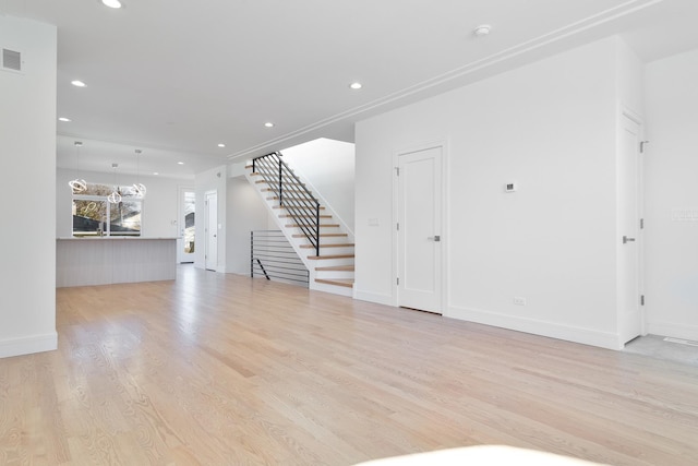 unfurnished living room featuring a chandelier and light wood-type flooring