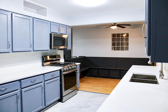 kitchen with decorative backsplash, ceiling fan, stainless steel appliances, and blue cabinets