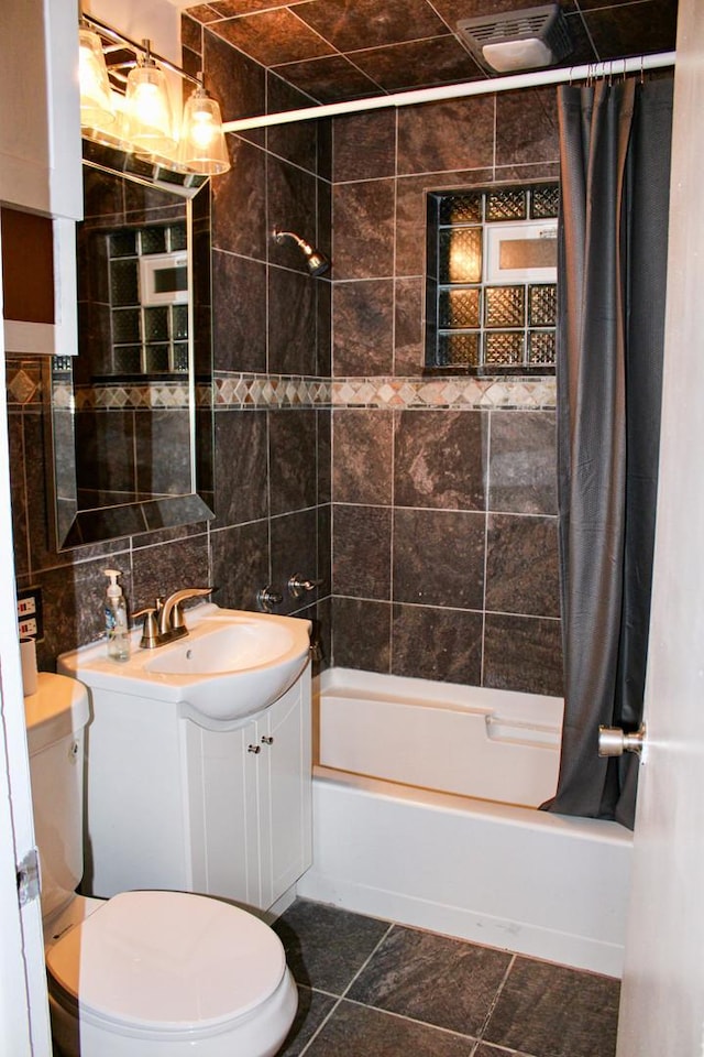 full bathroom featuring tile patterned floors, vanity, shower / bath combo with shower curtain, tile walls, and toilet