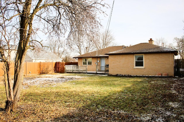 rear view of house with a wooden deck and a lawn