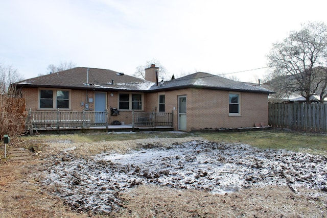 snow covered back of property with a wooden deck