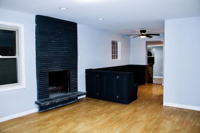 unfurnished living room featuring a fireplace, ceiling fan, and light hardwood / wood-style flooring