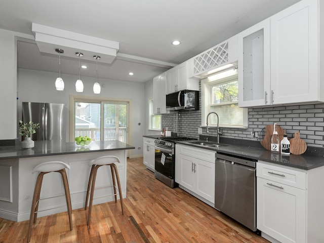 kitchen featuring pendant lighting, stainless steel appliances, white cabinetry, and sink