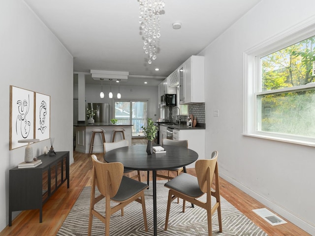 dining space with a wall mounted air conditioner and light hardwood / wood-style floors