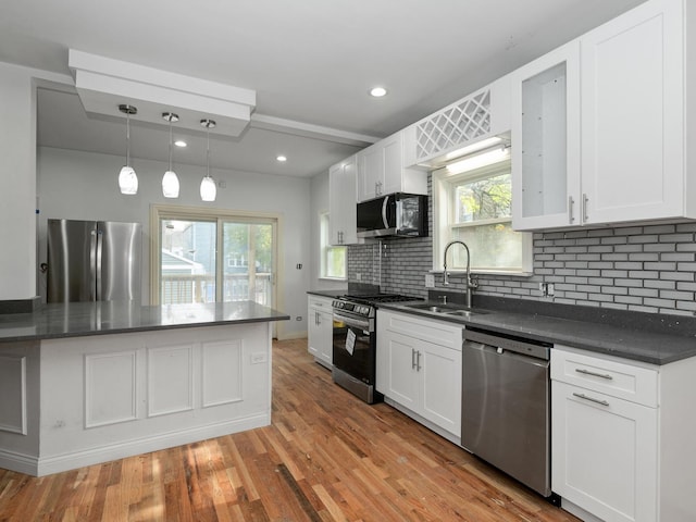 kitchen featuring backsplash, sink, appliances with stainless steel finishes, decorative light fixtures, and white cabinetry