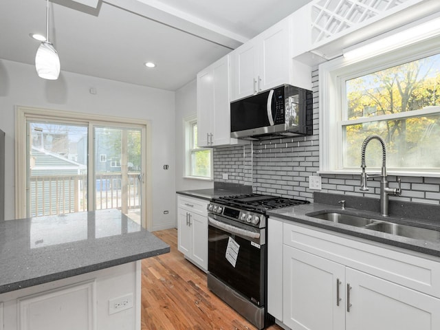 kitchen with pendant lighting, sink, light hardwood / wood-style flooring, white cabinetry, and stainless steel appliances