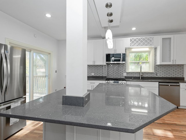 kitchen featuring white cabinetry, sink, dark stone countertops, a kitchen island, and appliances with stainless steel finishes