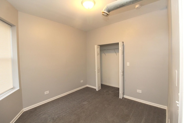 unfurnished bedroom featuring dark carpet and a closet