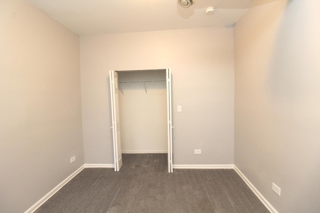 unfurnished bedroom with dark carpet and a closet