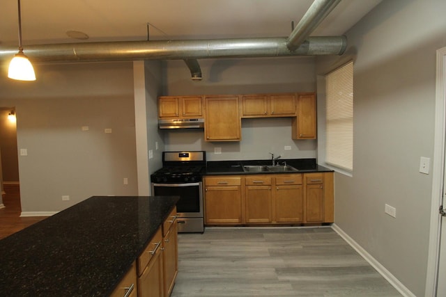 kitchen with pendant lighting, sink, light hardwood / wood-style floors, gas stove, and dark stone counters