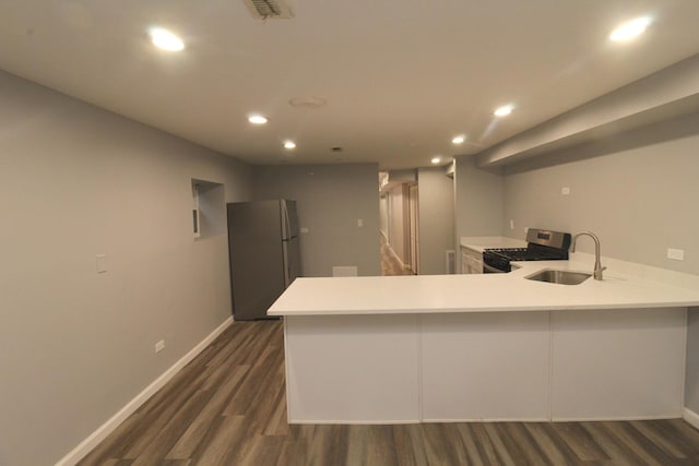 kitchen featuring appliances with stainless steel finishes, sink, dark hardwood / wood-style flooring, and kitchen peninsula