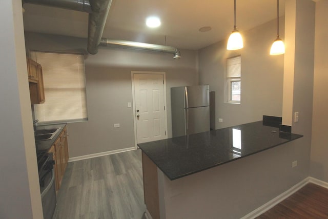 kitchen with a breakfast bar, hanging light fixtures, stainless steel refrigerator, dark hardwood / wood-style floors, and kitchen peninsula