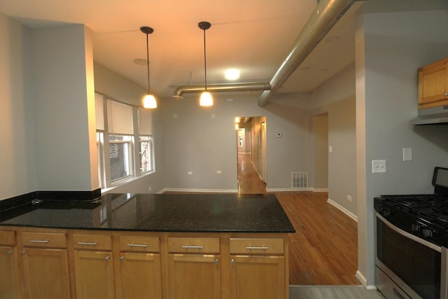 kitchen with hardwood / wood-style floors, decorative light fixtures, gas stove, and dark stone counters