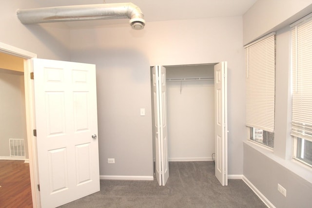 unfurnished bedroom featuring dark carpet and a closet