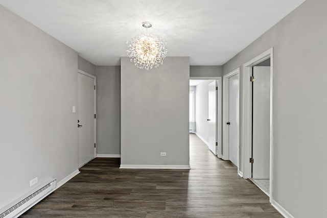 spare room with a chandelier, dark wood-type flooring, and a baseboard radiator