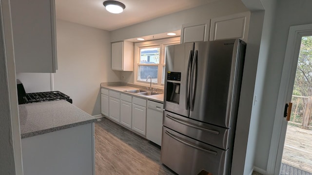 kitchen featuring gas stove, white dishwasher, a sink, stainless steel fridge, and light wood-type flooring