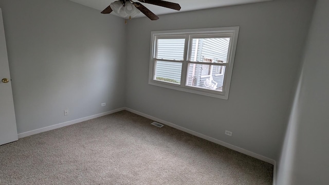 carpeted spare room with visible vents, baseboards, and ceiling fan