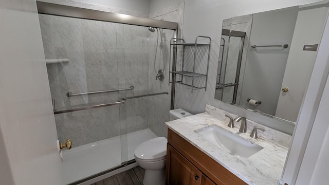 bathroom featuring a shower stall, toilet, vanity, and wood finished floors