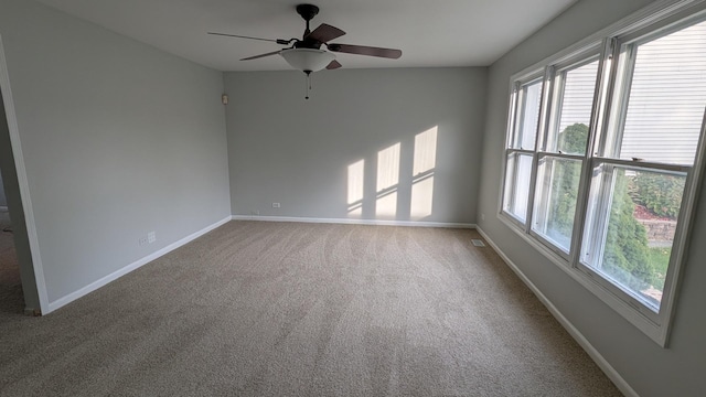 carpeted empty room with visible vents, ceiling fan, and baseboards