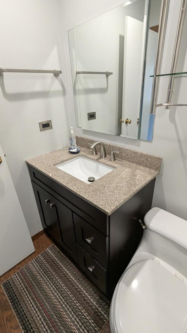 half bath featuring vanity, toilet, and wood finished floors