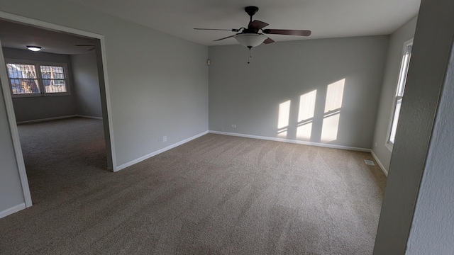 carpeted spare room featuring visible vents, ceiling fan, and baseboards