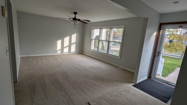 unfurnished room featuring carpet flooring, baseboards, visible vents, and a ceiling fan