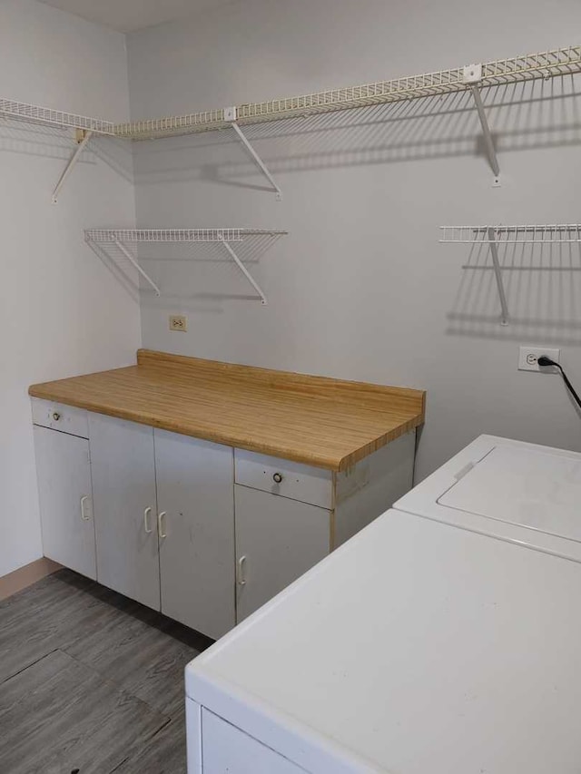 clothes washing area with washer / dryer, cabinet space, and dark wood-type flooring