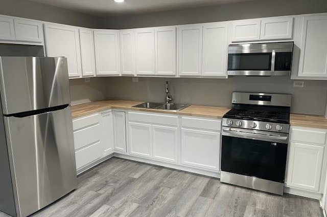 kitchen with light hardwood / wood-style floors, sink, white cabinetry, and appliances with stainless steel finishes