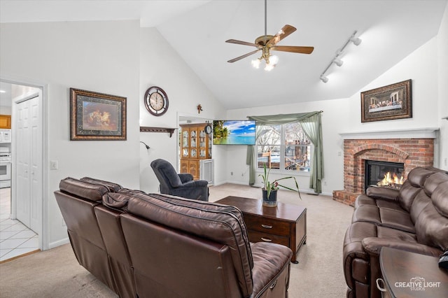 carpeted living room featuring a brick fireplace, high vaulted ceiling, track lighting, and ceiling fan