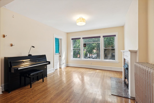 sitting room with a premium fireplace, radiator heating unit, a baseboard radiator, and hardwood / wood-style flooring