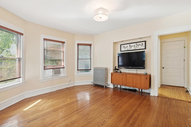 unfurnished living room featuring radiator and hardwood / wood-style flooring