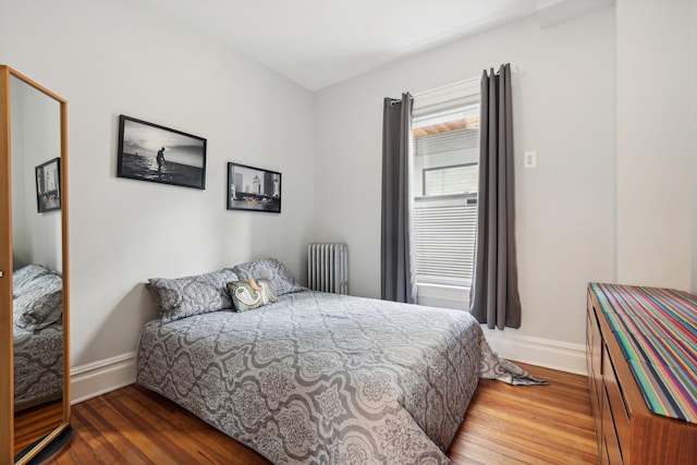 bedroom with radiator heating unit and wood-type flooring