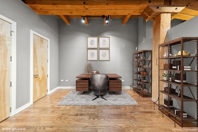 office featuring beamed ceiling, rail lighting, and light hardwood / wood-style flooring