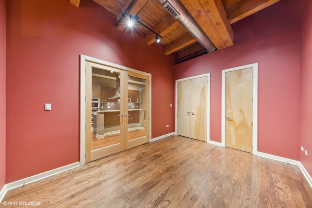 unfurnished bedroom with hardwood / wood-style flooring, beam ceiling, wooden ceiling, and rail lighting