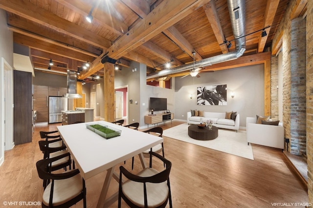 dining space featuring beamed ceiling, light wood-type flooring, rail lighting, and wooden ceiling