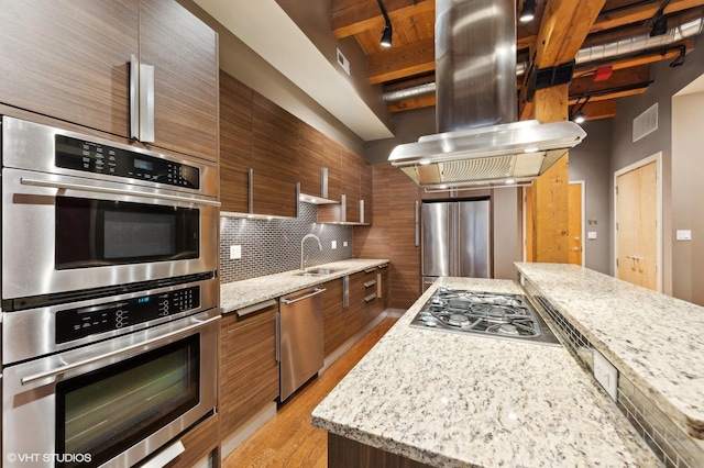 kitchen featuring backsplash, island range hood, sink, beam ceiling, and stainless steel appliances