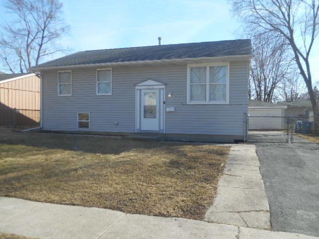 raised ranch featuring a garage, fence, and a front lawn