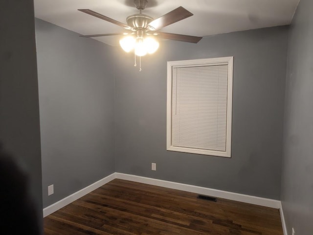 spare room featuring dark wood-type flooring, visible vents, baseboards, and a ceiling fan