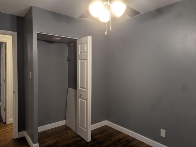 unfurnished bedroom with dark wood-style floors, a closet, and baseboards