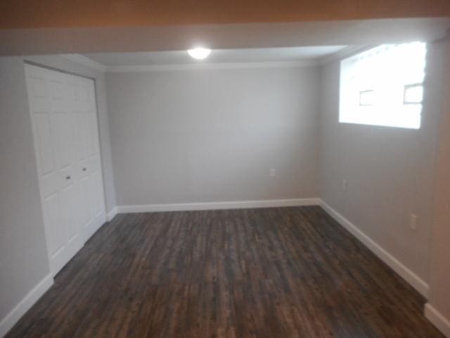 basement featuring baseboards, dark wood finished floors, and ornamental molding