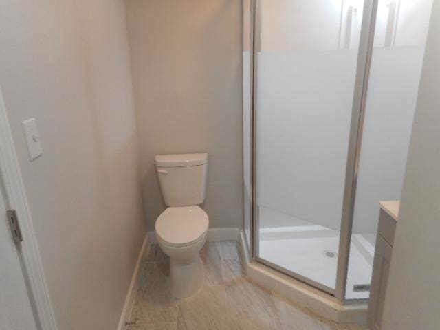 bathroom with a stall shower, baseboards, vanity, and toilet