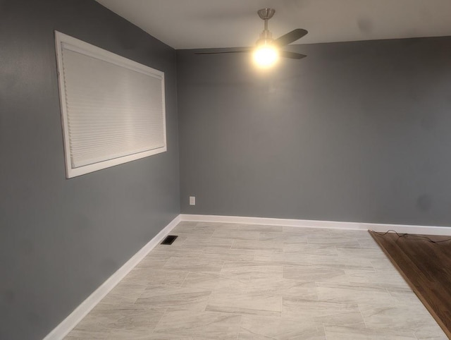 spare room featuring visible vents, ceiling fan, and baseboards